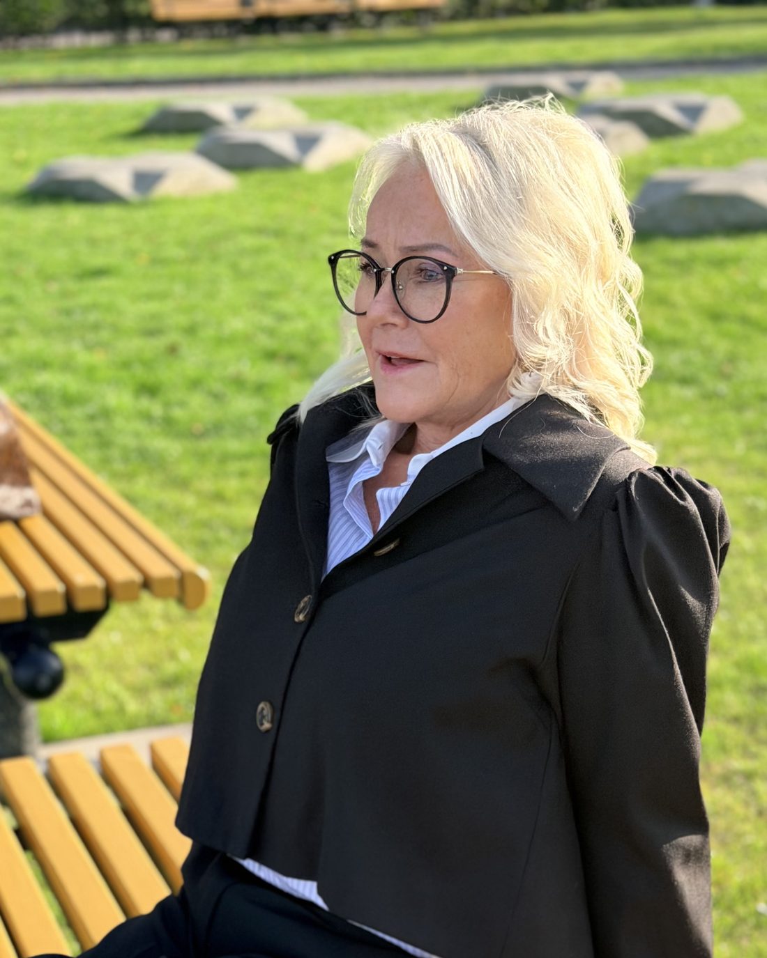 Torun Nordskaug sitter på en benk og ser ut over parken